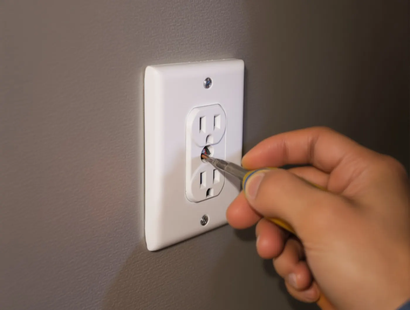 Electrician wiring a wall outlet